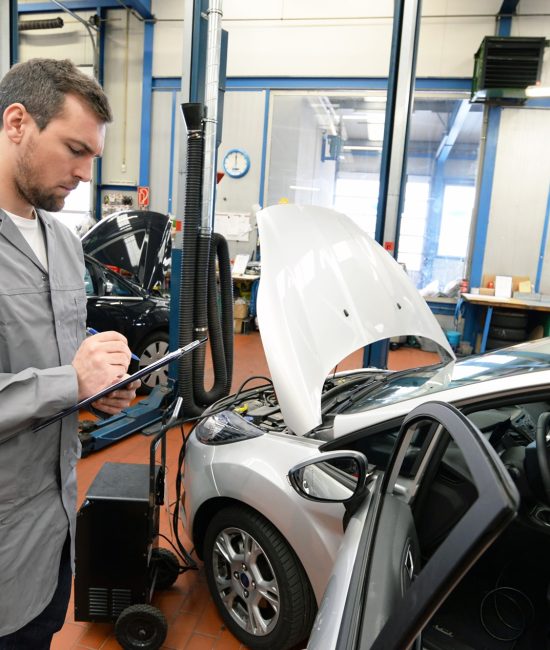 Gutachter prüft Fahrzeug in Autowerkstatt - TÜV